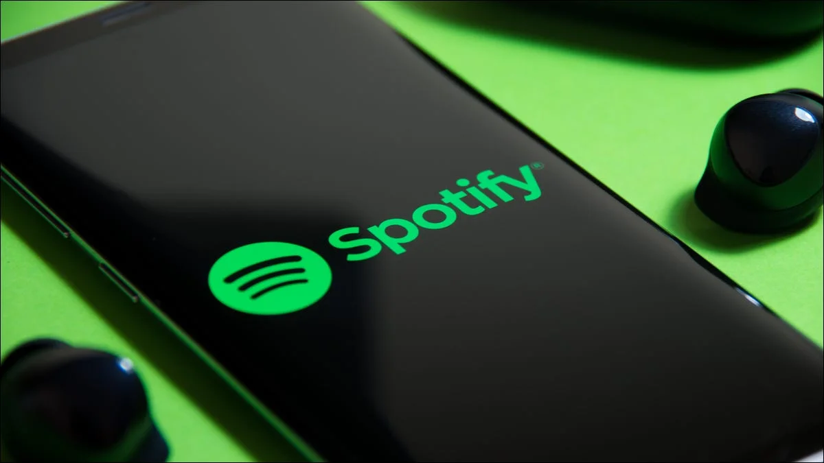 spotify-logo-on-a-smartphone-next-to-truly-wireless-earbuds اسپاتیفای