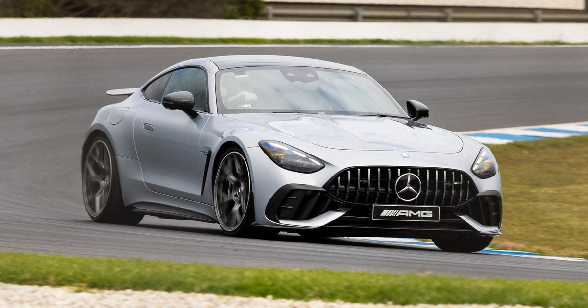 Silver Mercedes-AMG GT sports car around a bend on a race track, front three-quarter view