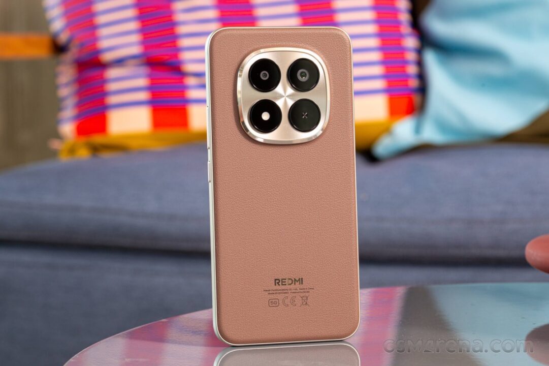 Back of a Redmi smartphone with a brown leather-textured finish and a quad-camera module in a metallic square frame on the top half of the phone.