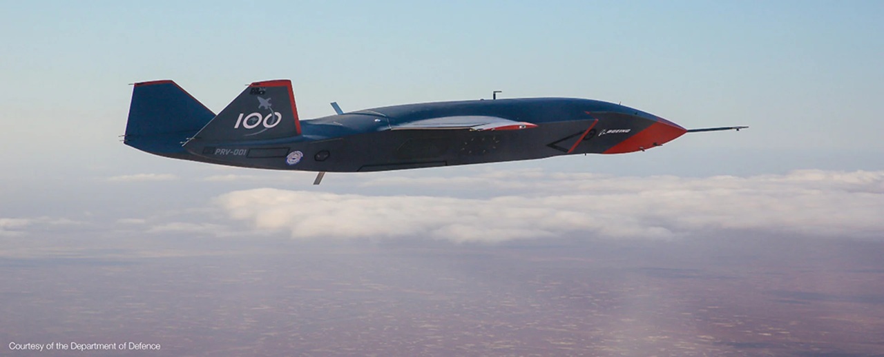mq-28aghost-bat Unmanned aerial vehicle with a blue fuselage and red nose flying above a cloudy horizon, marking '100' on the tail.