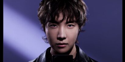 MUYTKOJSGBQTINRZGA4WKMJVGQ Close-up portrait of a young Asian man with tousled hair wearing a black leather jacket, under purple stage lighting.