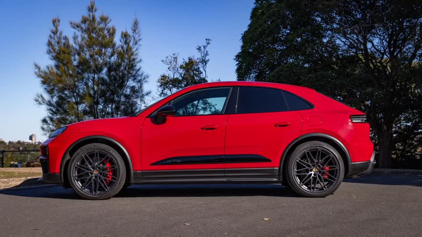 Side view of a red Porsche Macan SUV with black wheels and red brake calipers.