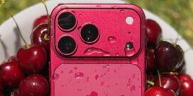 Pink iPhone with water droplets resting among fresh cherries in a white bowl, close-up shot.